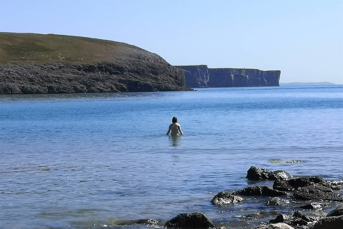 A photo of a Chloe from Chloe Evans Designs walking into the sea at Broadhaven South beach in Pembrokeshire for a swim.