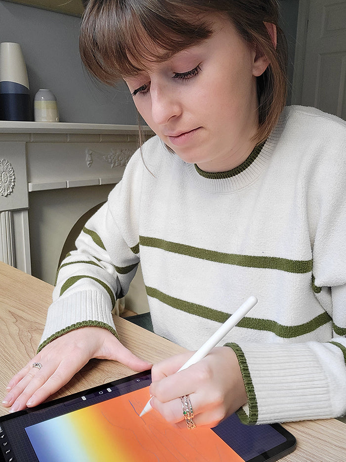 A photo of Chloe Evans from Chloe Evans Designs drawing a new design on her iPad.