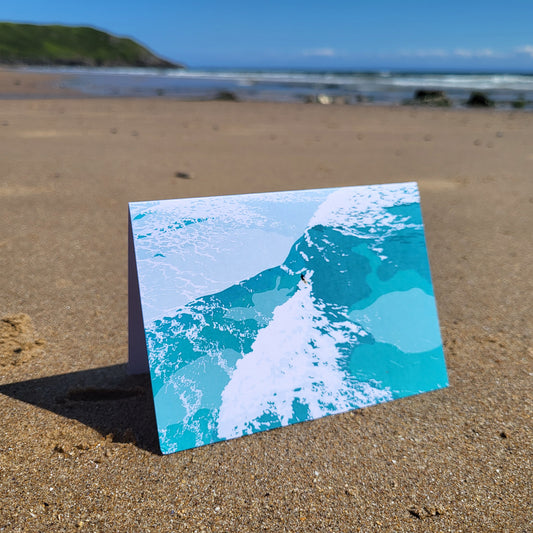 Card with a surfer wave design on a sandy beach