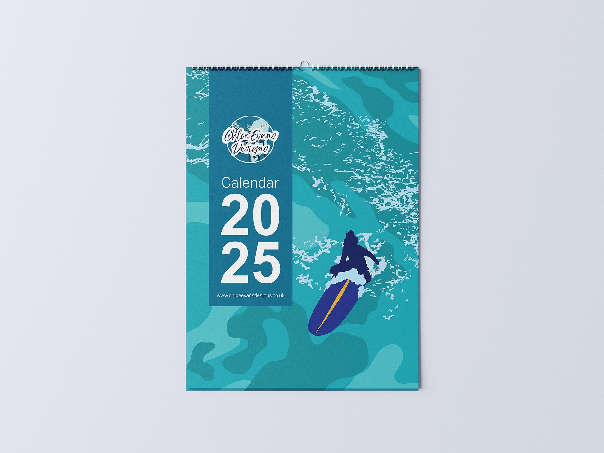 Digital mockup of an A3 coastal wall calendar, showing the cover with an illustration of a girl on a surfboard.