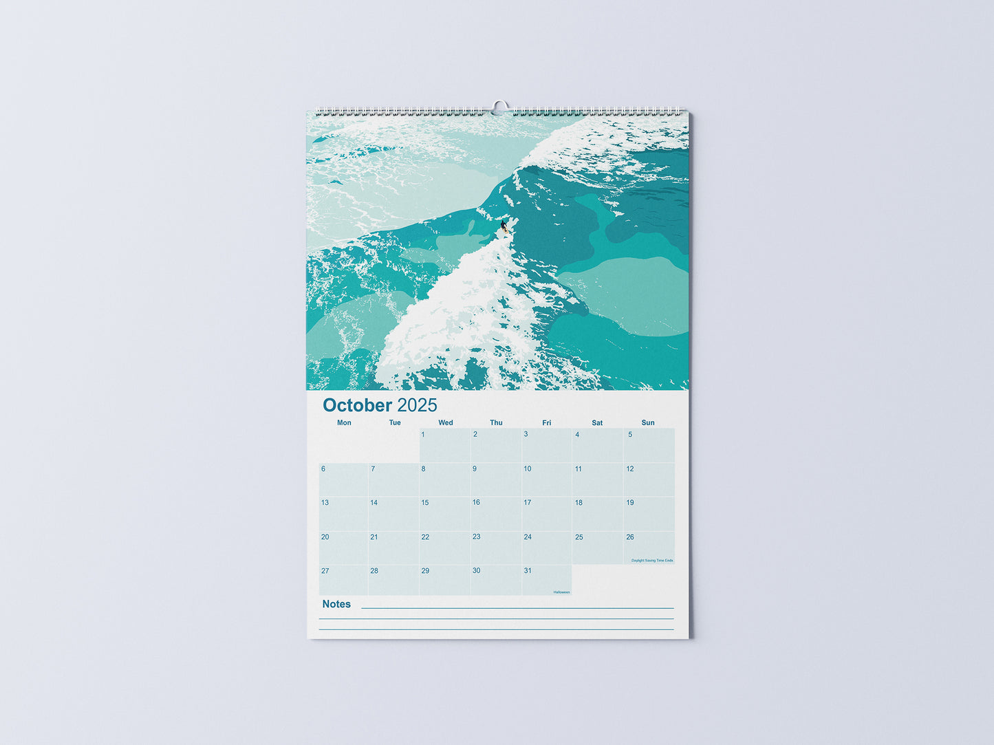 Digital mockup of an A3 coastal wall calendar, showing the October page with an illustration of a surfer riding a wave, surrounded by white water.