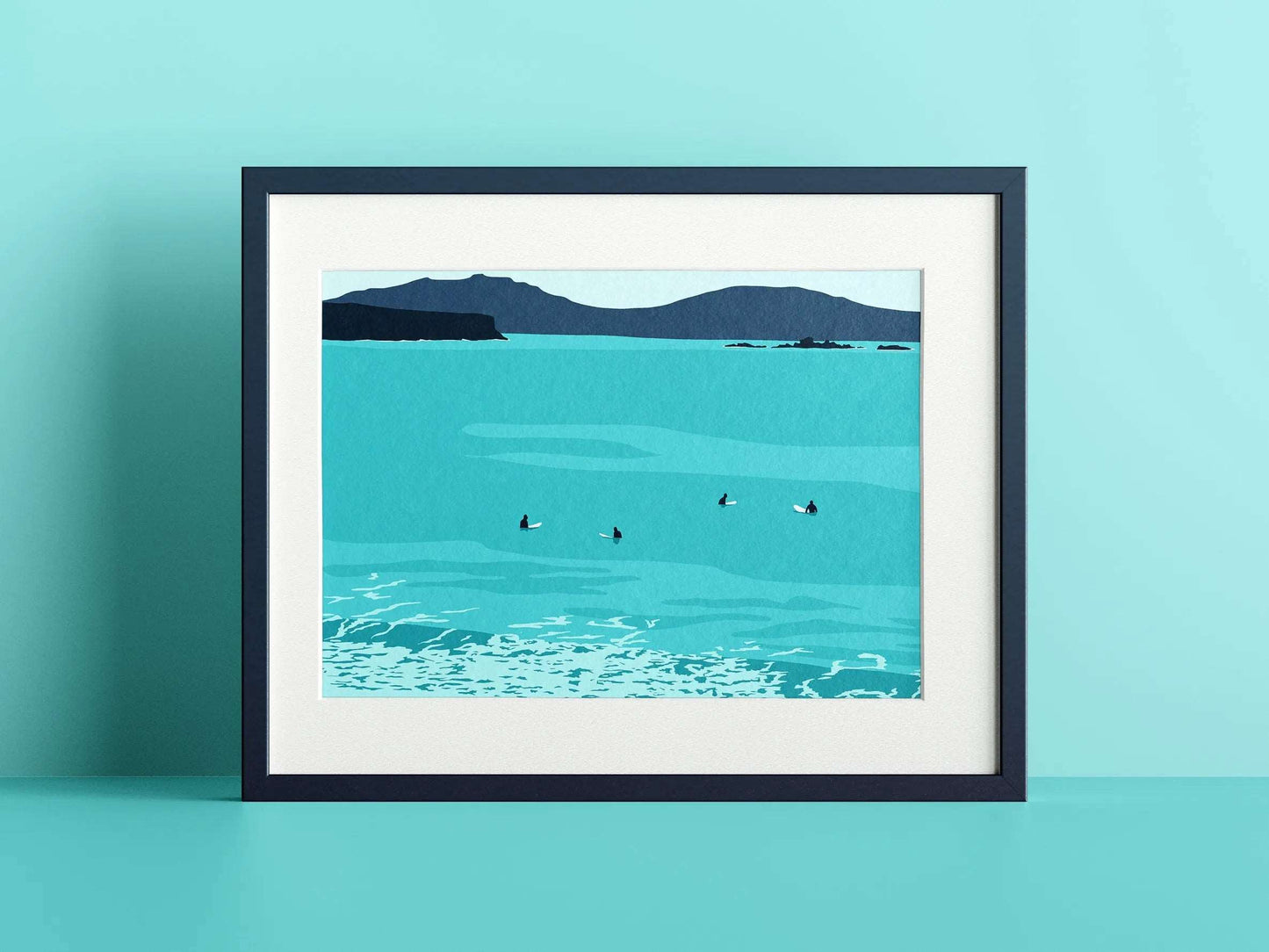 A blue print of surfers sat on the surfboards with an island in the distance, in a navy frame on a blue wall