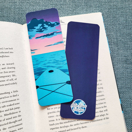 Bookmark showing the nose of a paddleboard on water at sunset with pink and purple sky – “Sunset SUP” design by Chloe Evans