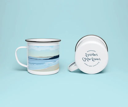 A white enamel mug from two perspectives: one of the mug on its side showing the branded base stamp on the bottom of the mug, and the other of the mug upright showing the blue print of Burry Port beach and lighthouse; all on a light blue background.