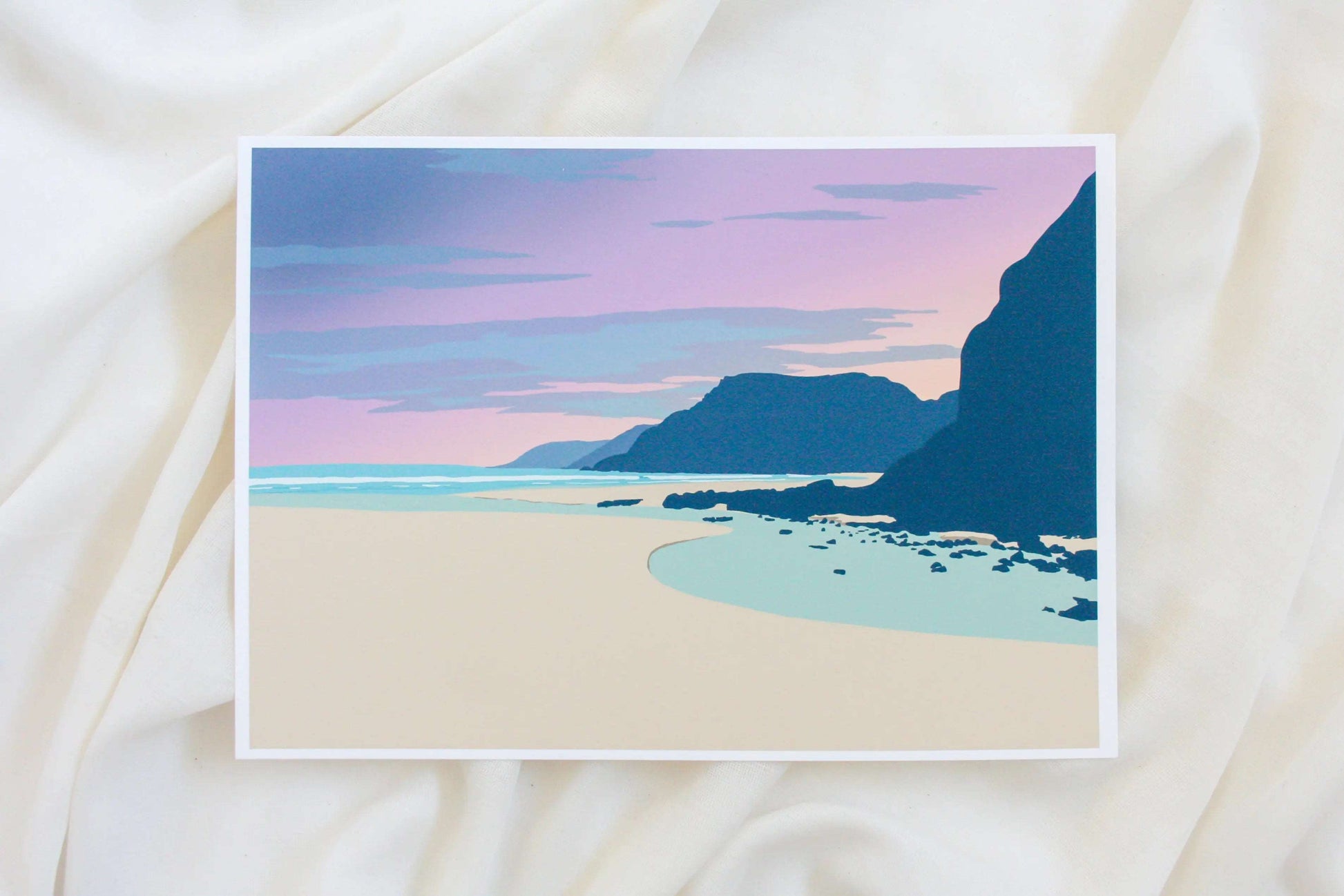 Photo of pink and blue Caswell bay sunset print on cream fabric backdrop.