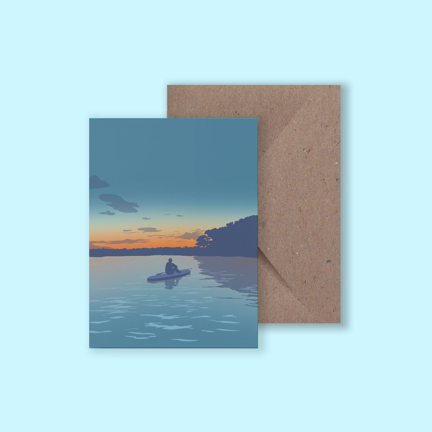 A mock up of a greeting card with an illustration of a paddleboarder sat on her board watching the sunset, with a brown envelope on a light blue background.