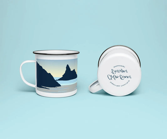 A mock up of a white enamel mug from two perspectives; one of the mug on its side looking at the bottom of the mug and the branded base stamp, and the other of the mug upright showing the print of an orange and blue beach scene, showing Church Rock and Broad Haven South, all on a light blue background.