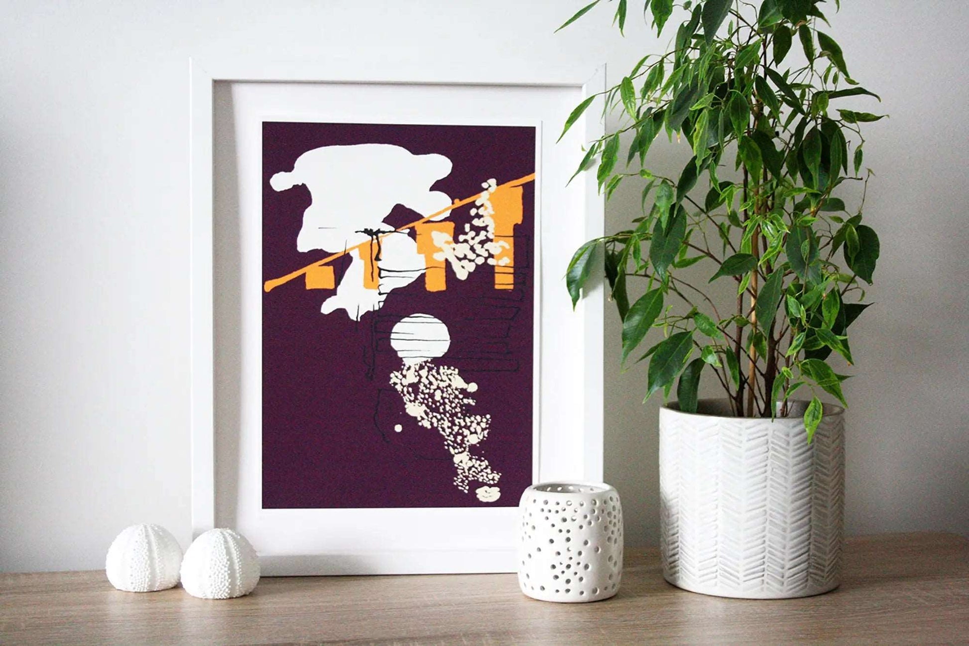 Photo of purple and yellow Coastal Journey 7 abstract A4 print in white frame, surrounded by white home accessories and house plant