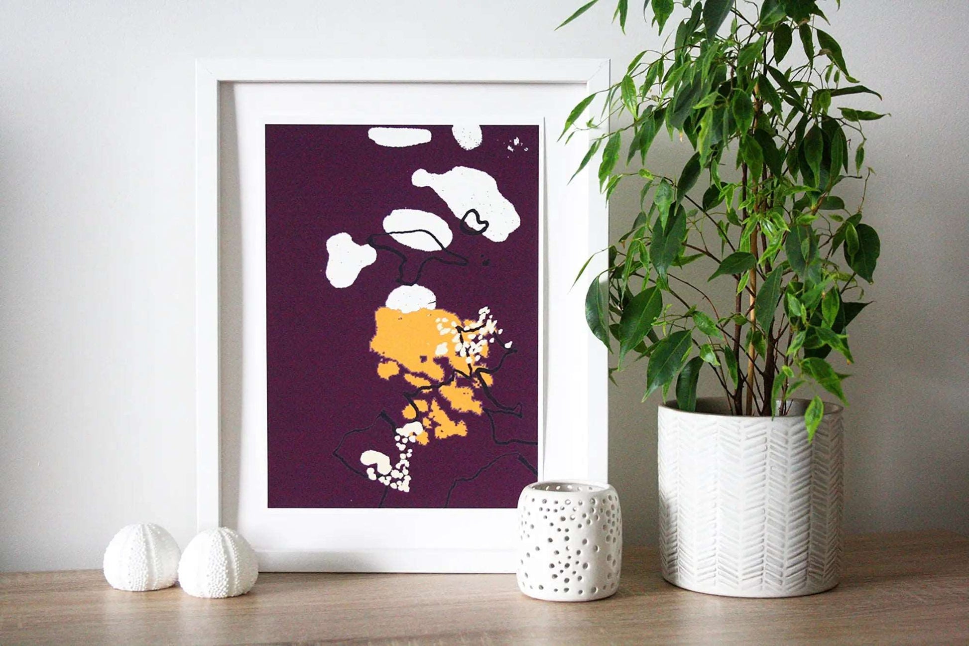 Photo of purple and yellow Coastal Journey 8 abstract A3+ print in white frame, surrounded by white home accessories and house plant