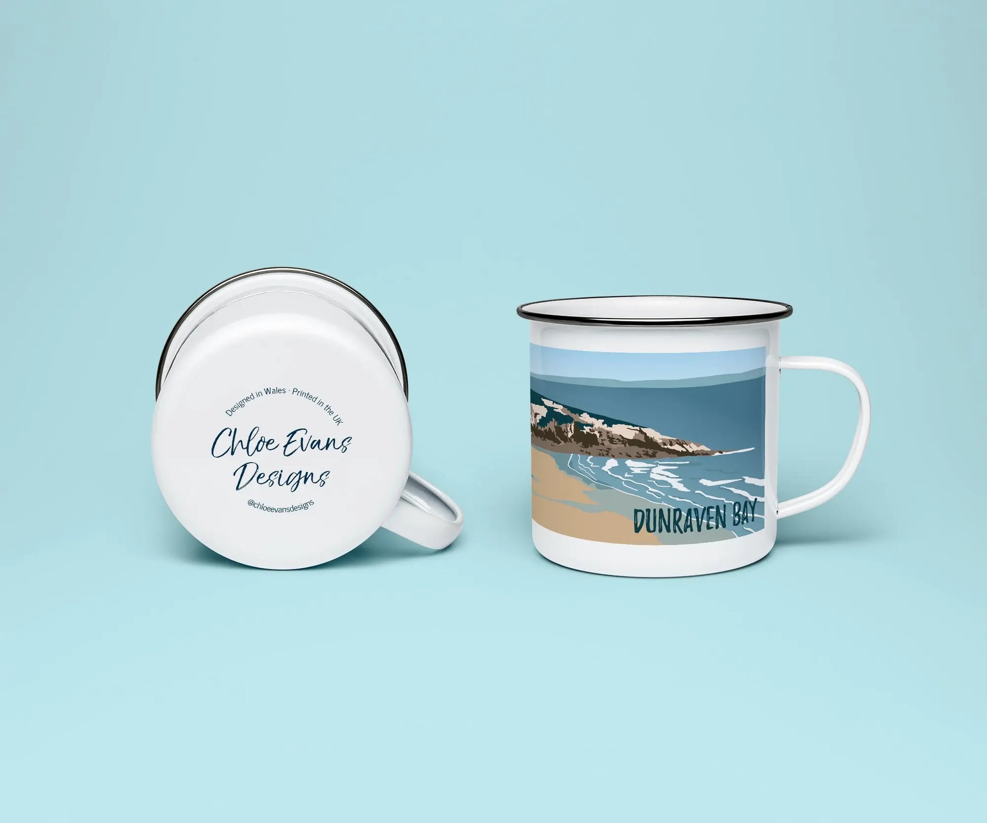 A white enamel mug from two perspectives: one of the mug on its side showing the branded base stamp on the bottom of the mug, and the other of the mug upright showing Dunraven bay, or Southerndown beach,; all on a light blue background.