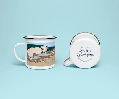 A white enamel mug from two perspectives: one of the mug on its side showing the branded base stamp on the bottom of the mug, and the other of the mug upright showing Dunraven bay, or Southerndown beach,; all on a light blue background.