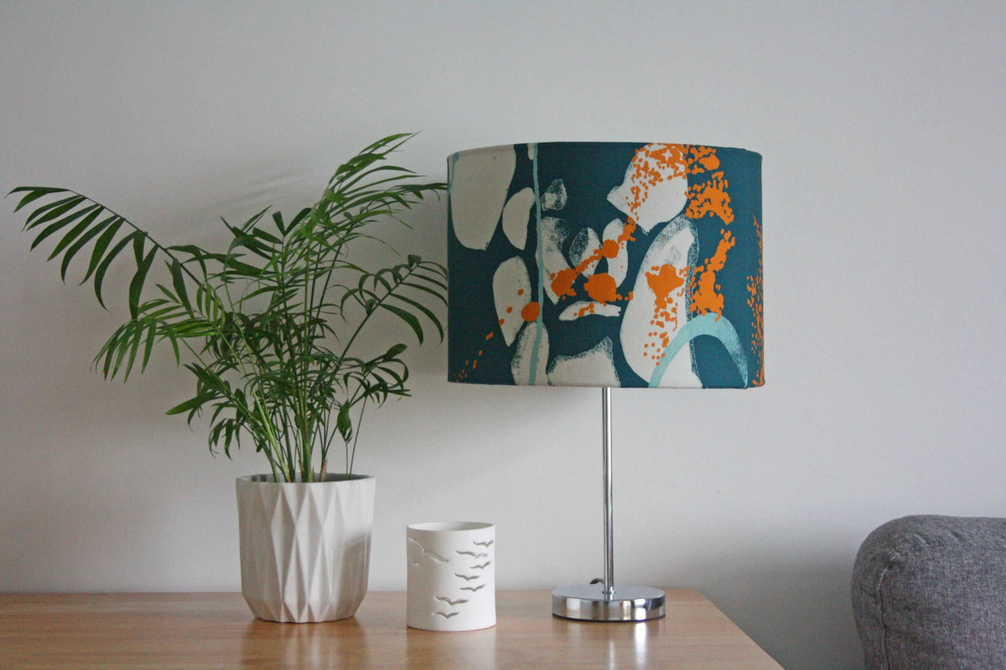 Digital mockup of 30cm green and orange abstract print handmade lampshade on silver table lamp with plant and home accessories