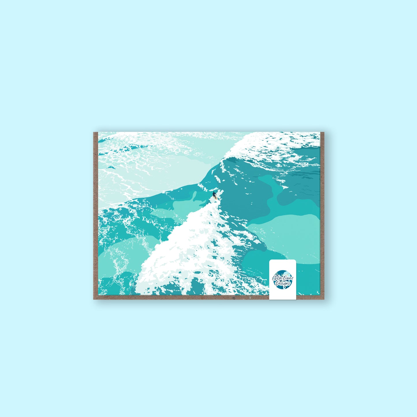 A mockup of a greeting card with an illustration of a surfer riding a wave on the front, with a brown envelope behind and a removable plastic-free sticker, on a light blue background.