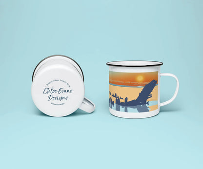 A white enamel mug from two perspectives: one of the mug on its side showing the branded base stamp on the bottom of the mug, and the other of the mug upright showing the blue and orange illustration of the Helvetia shipwreck on Rhossili beach at sunset; all on a light blue background.