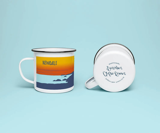 A mock up of a white enamel mug from two perspectives; one of the mug on its side looking at the bottom of the mug and the branded base stamp, and the other of the mug upright showing the print of an orange and blue beach scene, showing Newgale beach at sunset, all on a light blue background.