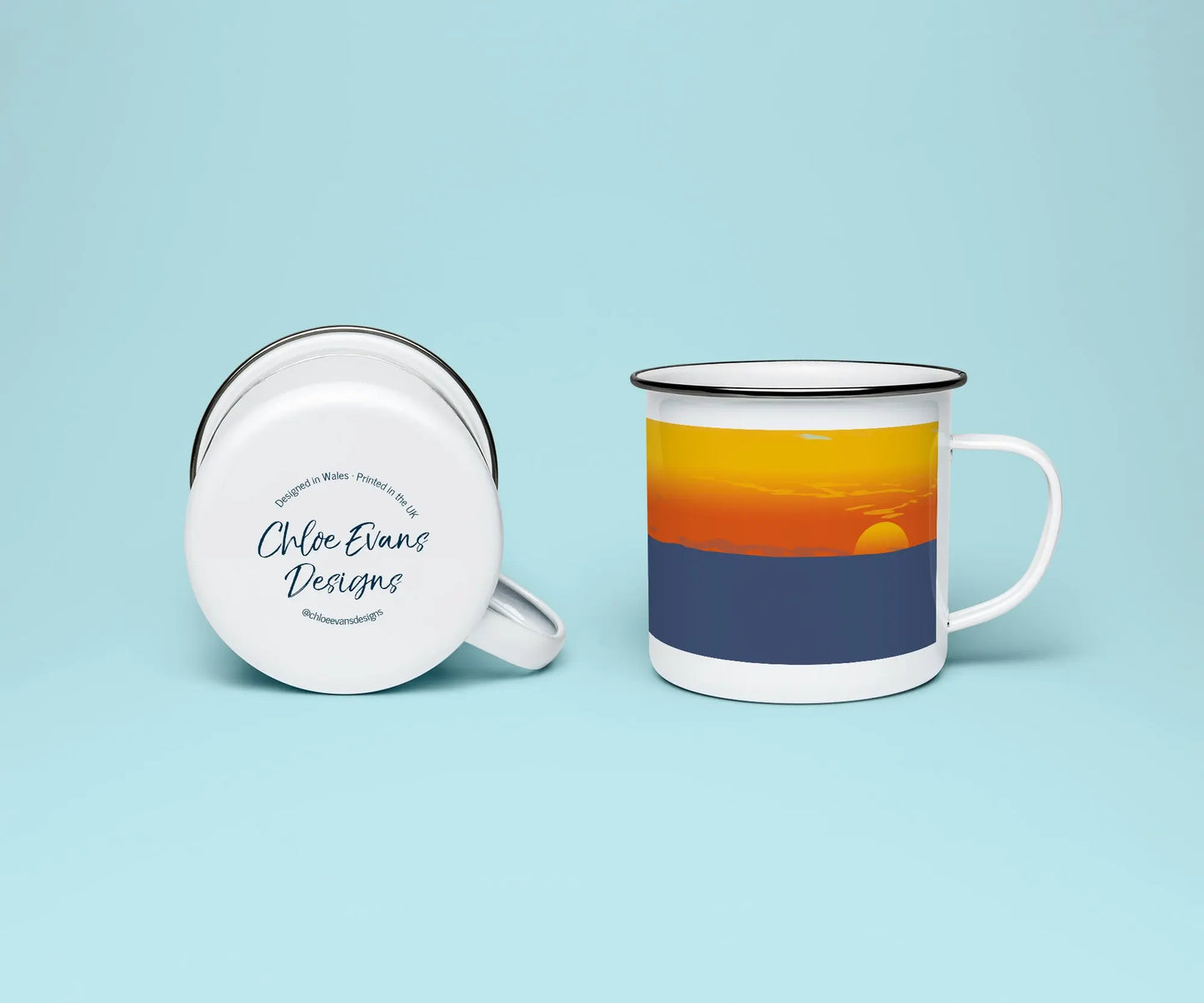 A mock up of a white enamel mug from two perspectives; one of the mug on its side looking at the bottom of the mug and the branded base stamp, and the other of the mug upright showing the print of an orange and blue beach scene, showing Newgale beach at sunset, all on a light blue background.