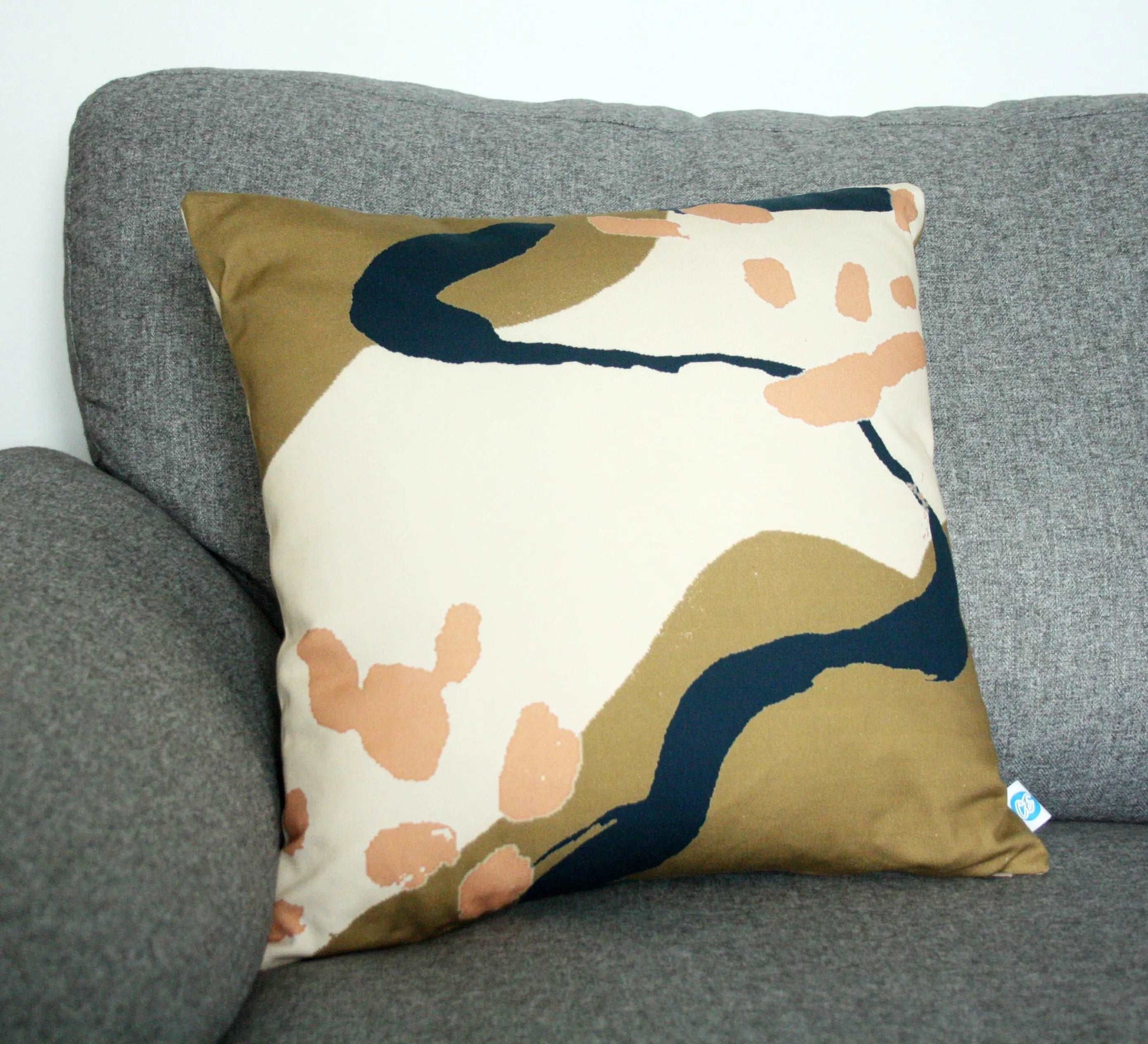 Photo of pink, brown and blue abstract printed cotton handmade cushion on grey sofa