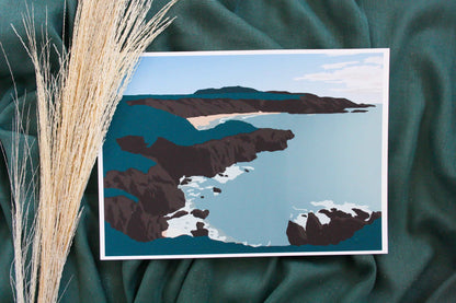 Photo of green, brown and blue Porthor beach print on green fabric backdrop and pampas grass.