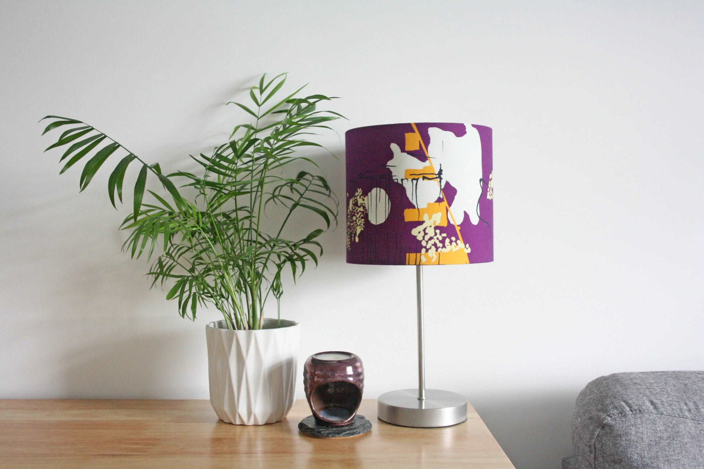 Photo of 20cm purple and yellow abstract handmade lampshade on silver table lamp with plant and oil burner