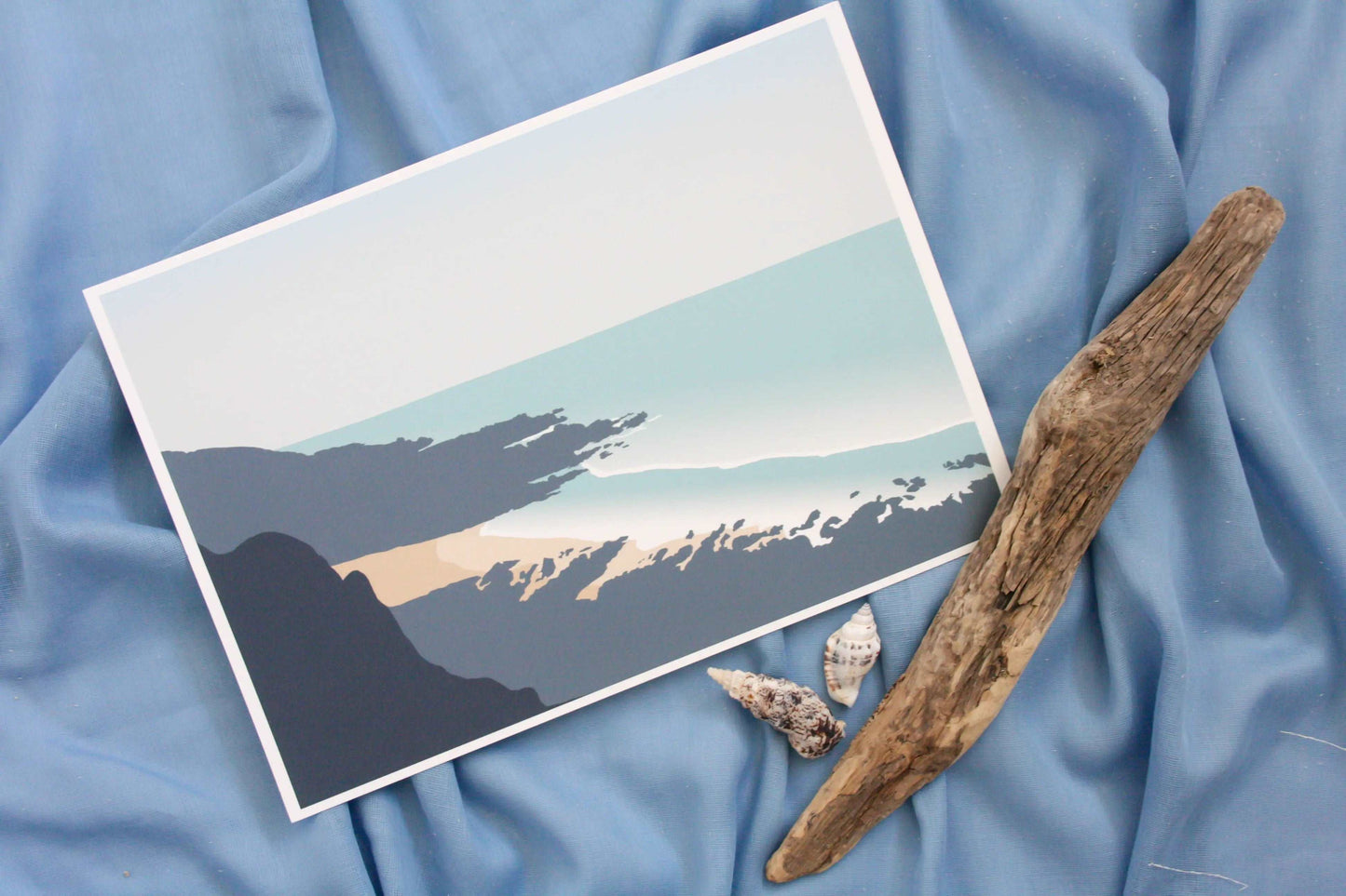 Photo of Rotherslade beach print on blue fabric backdrop and driftwood and shells