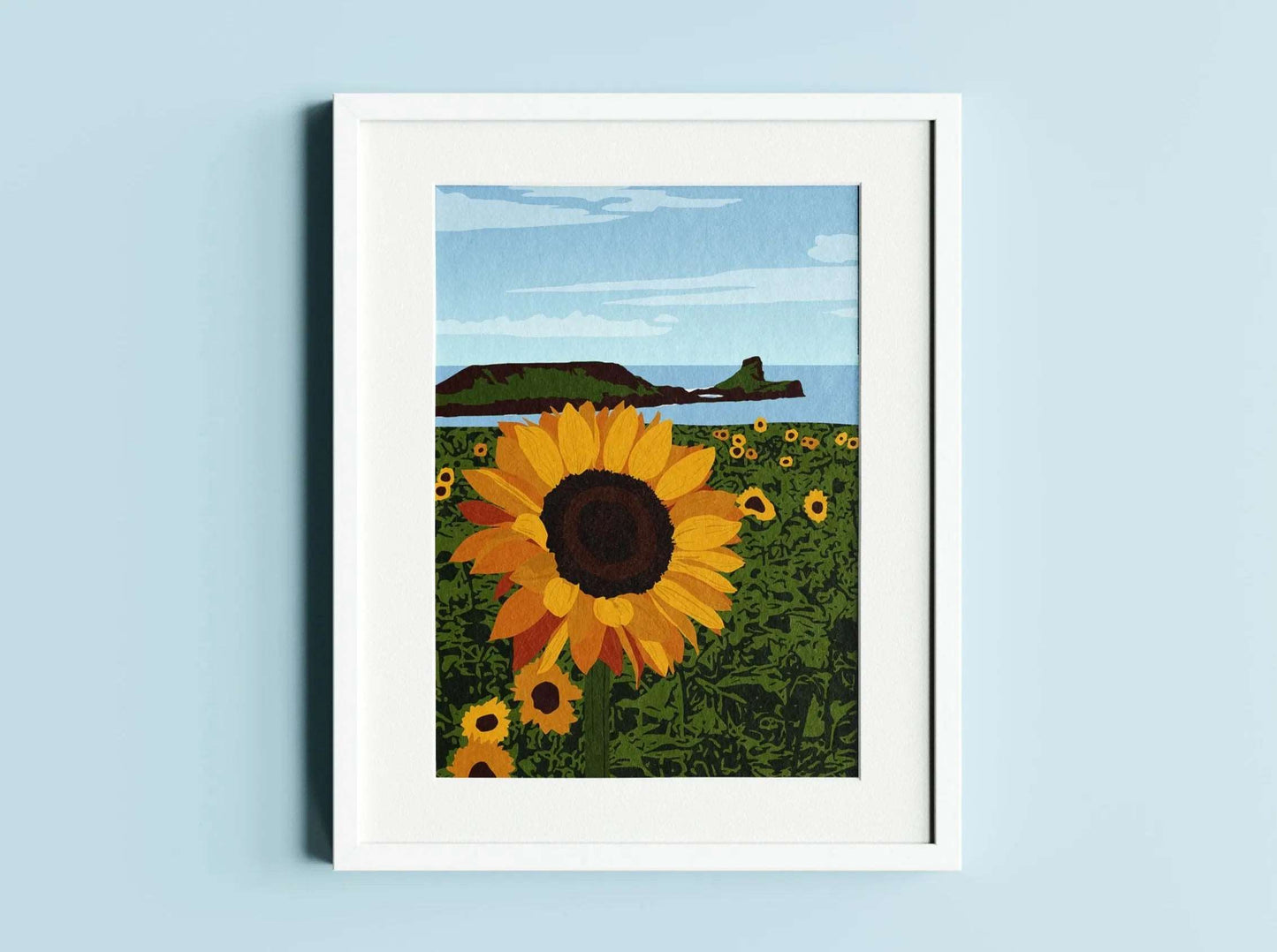 A yellow, green and blue illustration of a sunflower field with a coastal view of Worms Head in the background, in a white frame on a blue wall