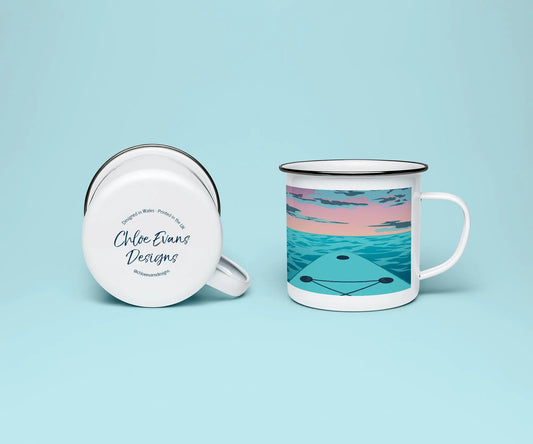 A white enamel mug from two perspectives: one of the mug on its side showing the branded base stamp on the bottom of the mug, and the other of the mug upright showing the pink and blue print of paddleboard on the sea with the sunset on the horizon; all on a light blue background.