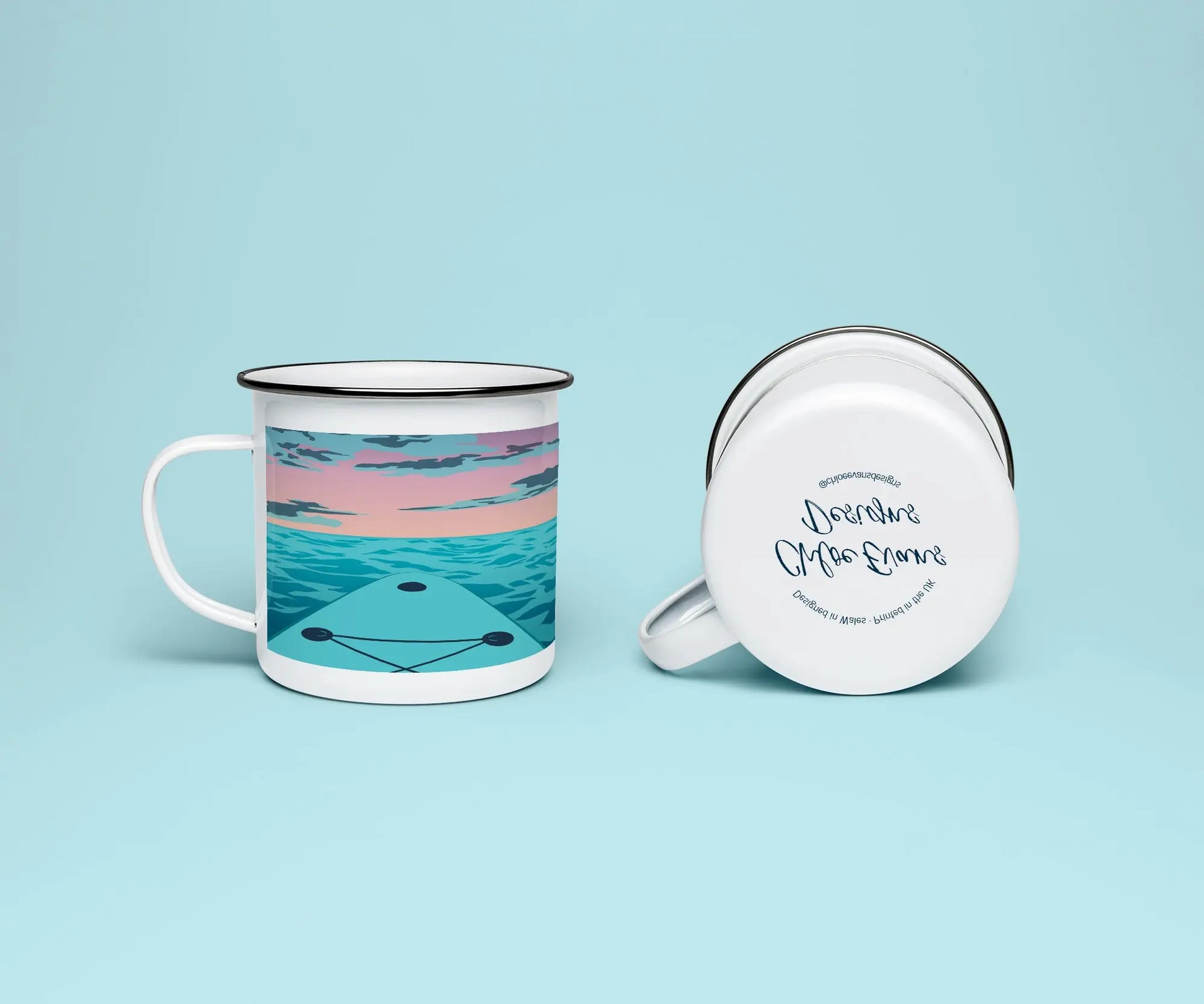 A white enamel mug from two perspectives: one of the mug on its side showing the branded base stamp on the bottom of the mug, and the other of the mug upright showing the pink and blue print of paddleboard on the sea with the sunset on the horizon; all on a light blue background.