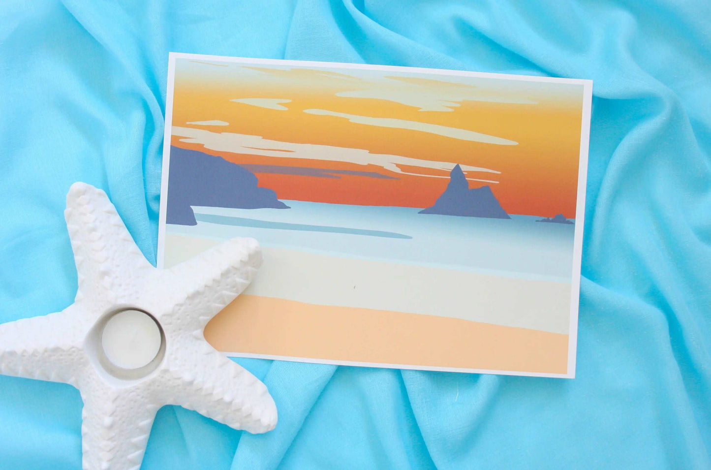 Photo of orange and blue Broad Haven South beach sunset print on blue fabric backdrop and starfish tealight holder