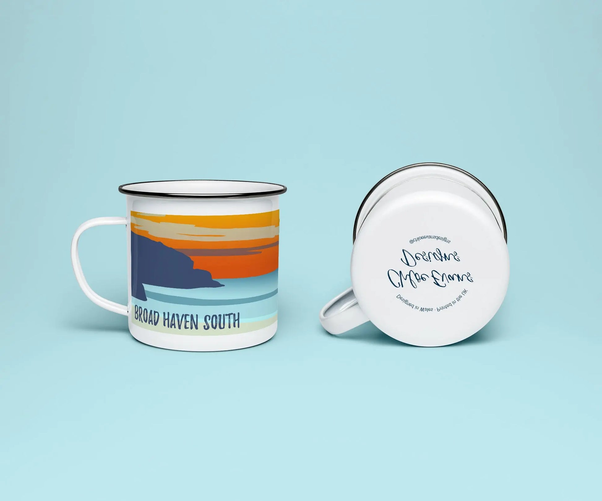 A mock up of a white enamel mug from two perspectives; one of the mug on its side looking at the bottom of the mug and the branded base stamp, and the other of the mug upright showing the print of an orange and blue beach scene, showing Church Rock and Broad Haven South at sunset, all on a light blue background.