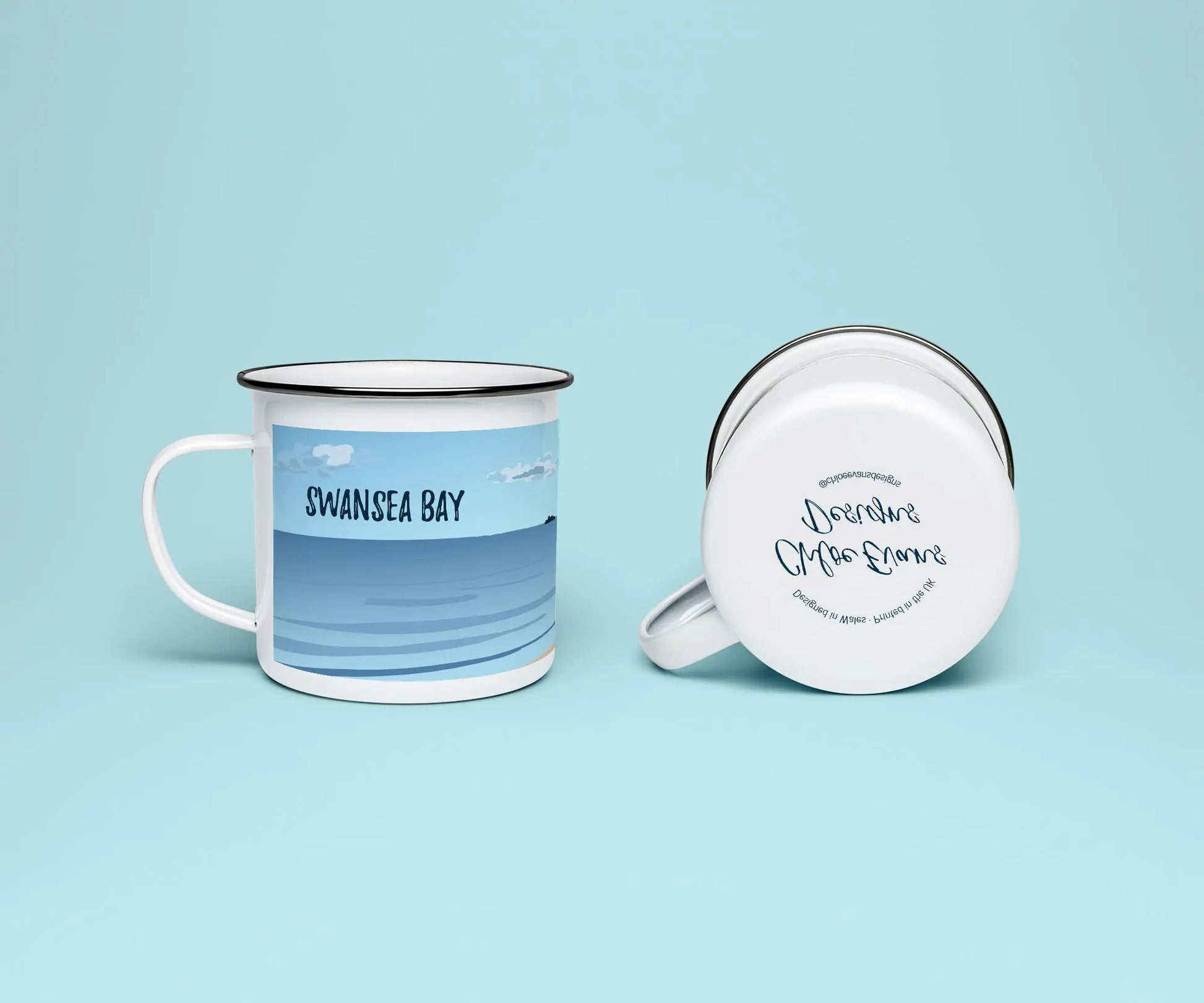 A mock up of a white enamel mug from two perspectives; one of the mug on its side looking at the bottom of the mug and the branded base stamp, and the other of the mug upright showing the print of an orange and blue beach scene, showing Swansea bay and Mumbles Pier, all on a light blue background.