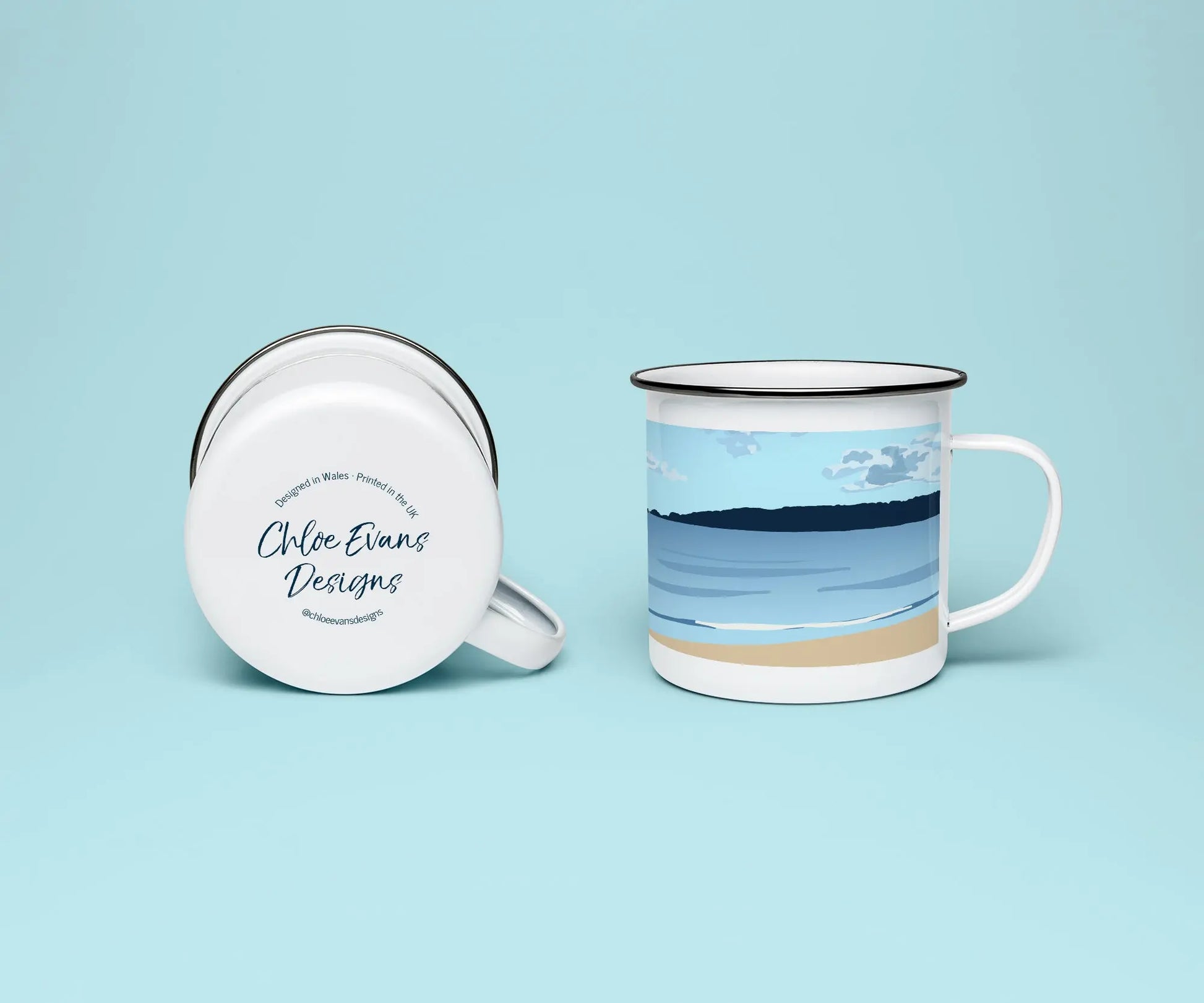 A mock up of a white enamel mug from two perspectives; one of the mug on its side looking at the bottom of the mug and the branded base stamp, and the other of the mug upright showing the print of an orange and blue beach scene, showing Swansea bay and Mumbles Pier, all on a light blue background.