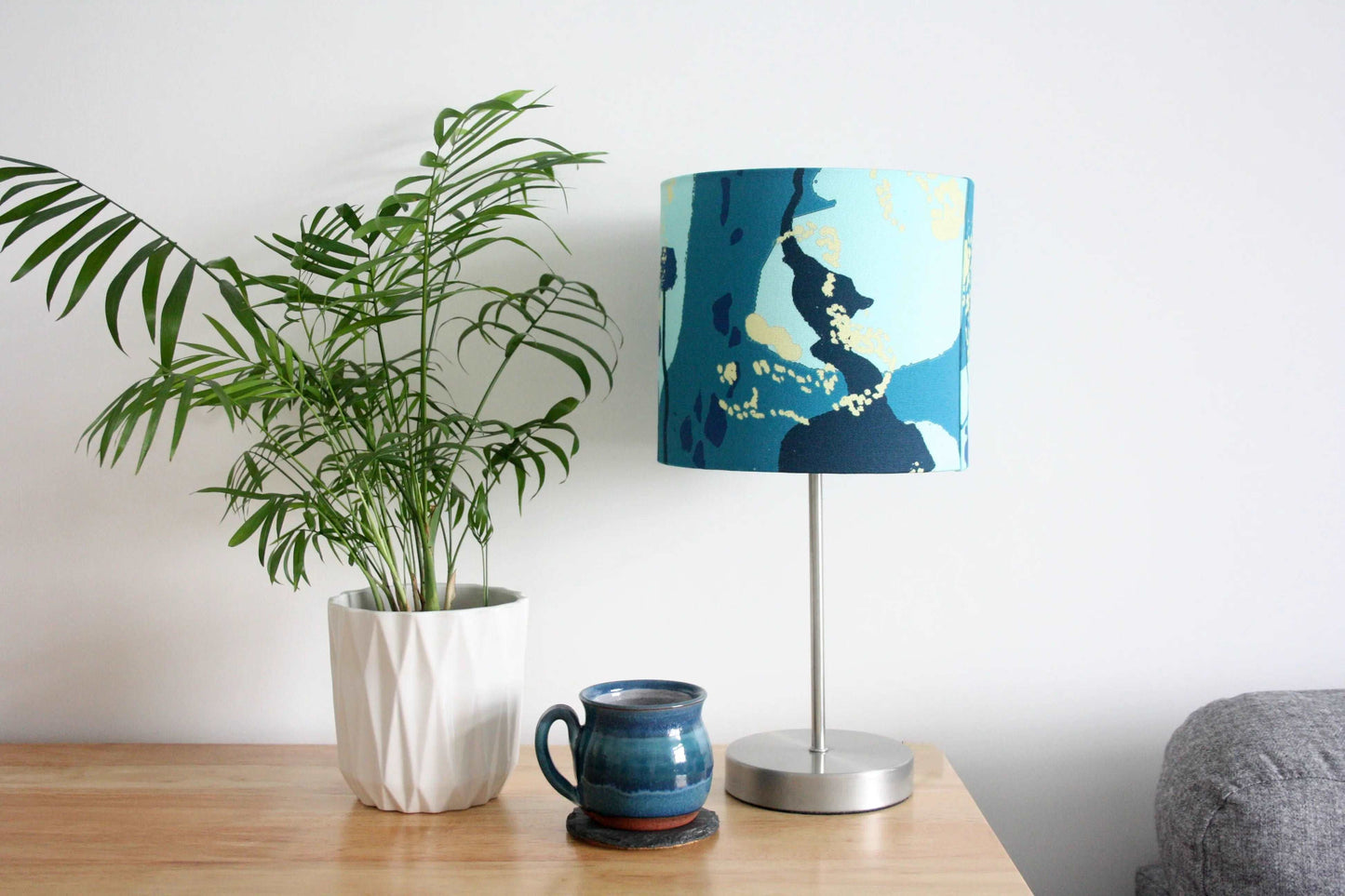 Photo of 20cm teal and blue abstract handmade lampshade on silver table lamp with blue mug and house plant