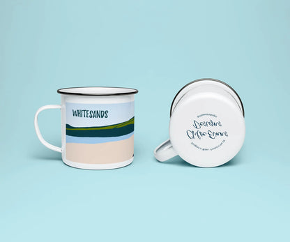 A mock up of a white enamel mug from two perspectives; one of the mug on its side looking at the bottom of the mug and the branded base stamp, and the other of the mug upright showing the print of an green, grey, and blue beach scene, showing Whitesands beach, all on a light blue background.